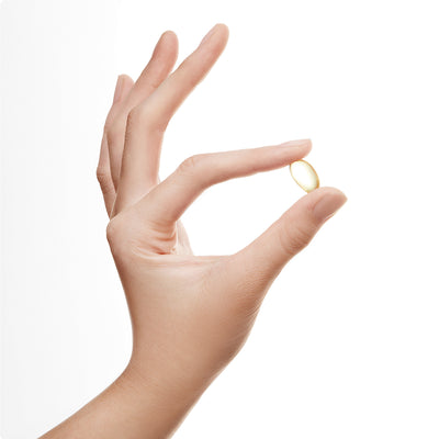 Hand holding a small yellow DHA fish oil gel capsule between thumb and index finger