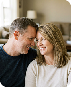 Smiling middle-aged couple sharing a tender moment indoors, looking at each other warmly