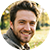 Smiling man with beard and curly brown hair in circular cropped photo