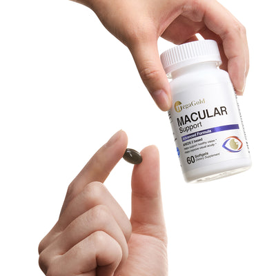 Hand holding MegaGold Macular Support softgel bottle with one dark capsule pinched between fingers