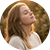 Woman with closed eyes, tilting head back in sunlight, warm golden tones, peaceful expression outdoors